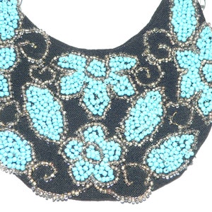 May include: A black fabric crescent-shaped applique with a design of turquoise blue beads in a floral pattern.