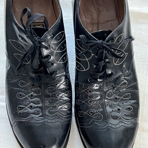 May include: A pair of black leather lace-up shoes with decorative stitching and a white label on the inside that reads "Fashioned for Ladies Verified".
