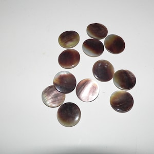 May include: A collection of 12 round, iridescent, mother-of-pearl buttons in shades of brown, white, and green.