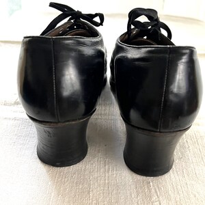 May include: A pair of black leather heeled shoes with lace-up closures. The shoes have a rounded toe and a low block heel.