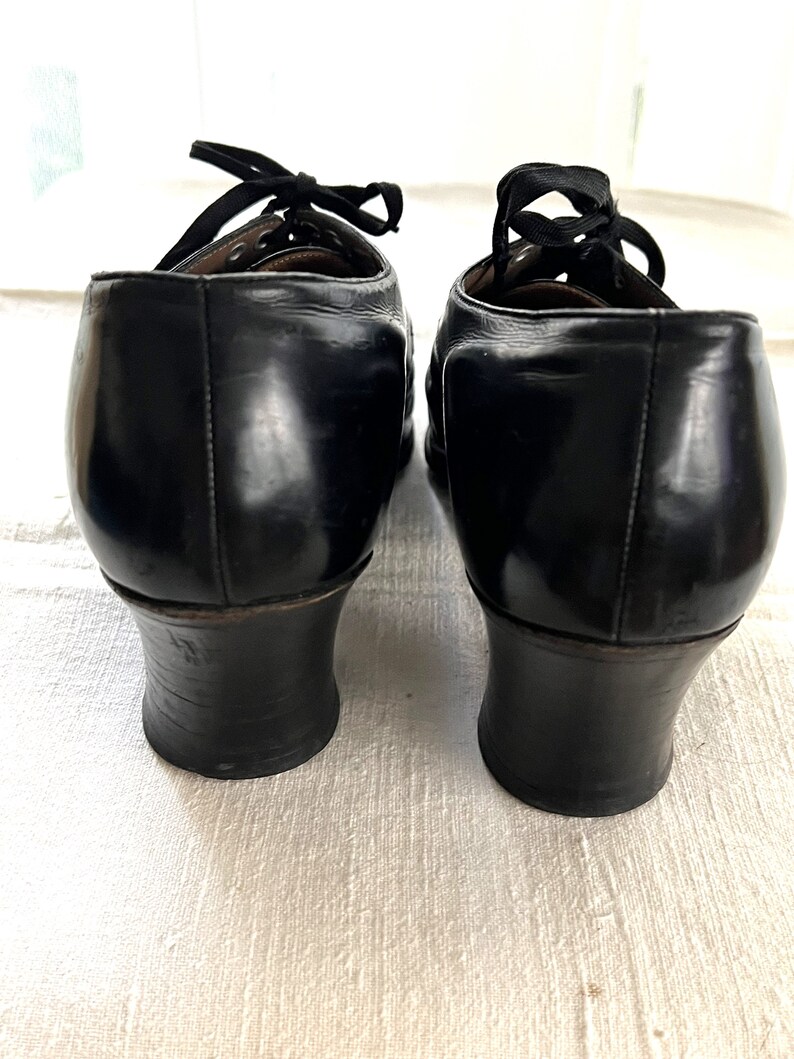 May include: A pair of black leather heeled shoes with lace-up closures. The shoes have a rounded toe and a low block heel.