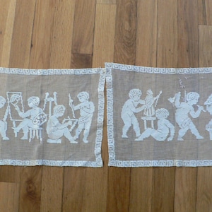 Puede incluir: Dos paneles de encaje blanco con imágenes bordadas de personas en un entorno clásico. Los paneles tienen un borde blanco de clave griega.