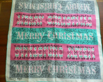 May include: A vintage Christmas-themed handkerchief with the words "MERRY CHRISTMAS" in white script and decorative flourishes. The design features alternating bands of pink, teal, and gray, with a white border. The artist's signature, "Tammis Keefe," is in the bottom left corner.