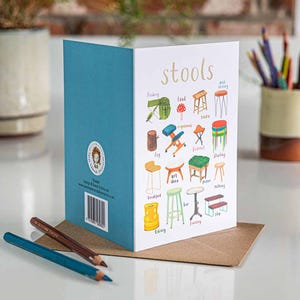 Può includere: Una carta illustrata colorata con la parola "stools" in caratteri dorati. La carta presenta vari tipi di sgabelli con etichette che descrivono i loro usi, come "pesca", "cibo", "art deco", "festival" e "biblioteca".