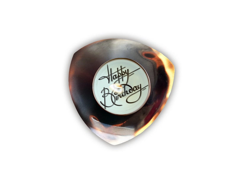 May include: A small, triangular, metal dish with a burnished copper finish. The dish has a white, round, center piece with the words "Happy Birthday" written in black script.