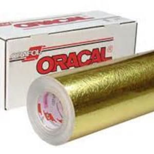 May include: A roll of gold-colored Oracal vinyl with a textured finish. The vinyl is wrapped around a cardboard core and is labeled with the Oracal brand name.