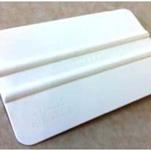 May include: White plastic squeegee with two raised ridges. The squeegee is used to smooth out air bubbles and wrinkles in vinyl decals and stickers.