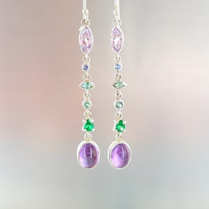 Könnte beinhalten: Ein Paar silberne Ohrhänger mit einer Kaskade aus Edelsteinen. Die Ohrringe sind mit Amethyst, grünen und blauen Edelsteinen besetzt.