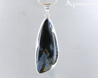 Peut inclure: Un pendentif en argent avec une pierre précieuse en œil de tigre bleu et noir. La pierre précieuse est sertie dans un cadre en argent et a une forme de larme.