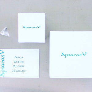 K&ouml;nnte beinhalten: Drei wei&szlig;e Boxen mit dem Text "Apsaras V" in blaugr&uuml;n. Die kleinste Box hat den Text "Gold Stone Silver Jewelry" in blaugr&uuml;n.
