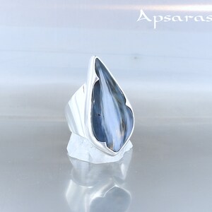 Peut inclure: Une bague en argent avec une pierre pr&eacute;cieuse bleu et blanc en forme de larme. La bague est pos&eacute;e sur un fond blanc.