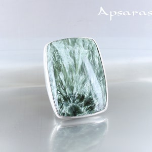 May include: A silver ring with a large, rectangular green gemstone. The gemstone has a swirling, marbled pattern.
