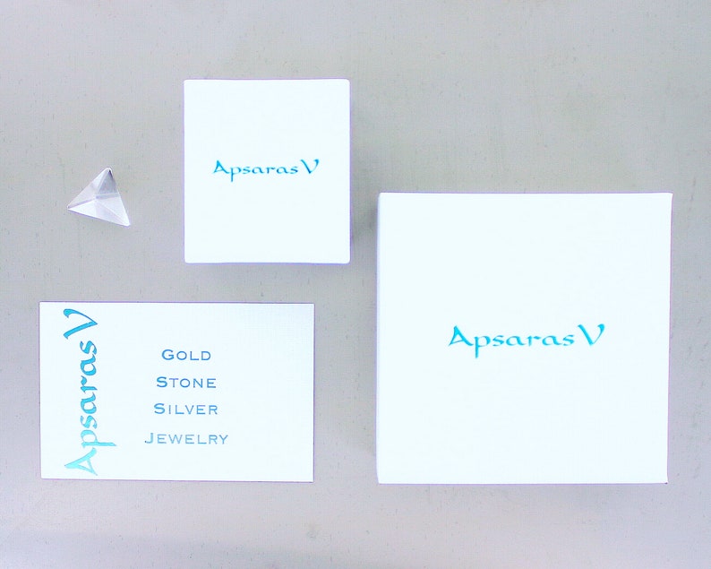 May include: Three white boxes with the text "Apsaras V" in teal blue. The smallest box has the text "Gold Stone Silver Jewelry" in teal blue.