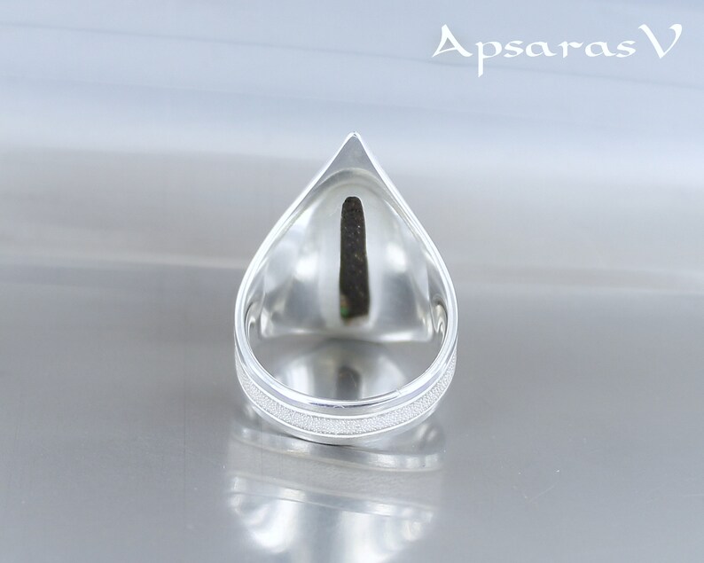 K&ouml;nnte beinhalten: Ein silberner Ring mit einem tropfenf&ouml;rmigen Design. Der Ring hat eine strukturierte Band und eine glatte, spitze Oberseite.