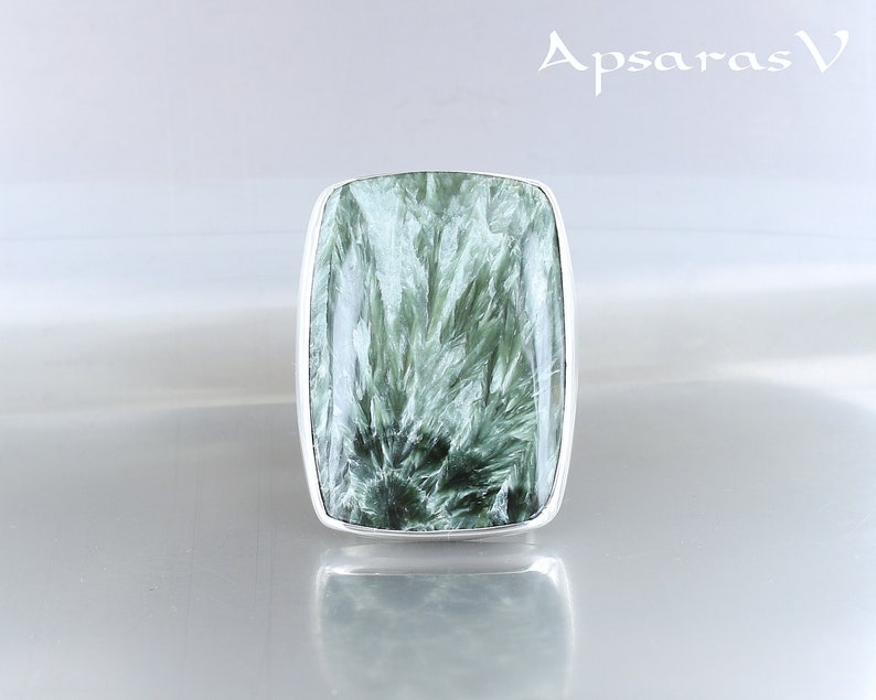 May include: A silver ring with a green and white gemstone. The gemstone has a unique, swirling pattern.