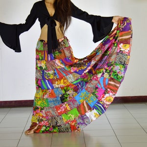 Puede incluir: Una falda larga de patchwork colorida con un top corto negro. La falda está hecha de muchas telas y patrones diferentes, y está fruncida en la cintura. El top es un estilo simple y ajustado con un lazo en la parte delantera.
