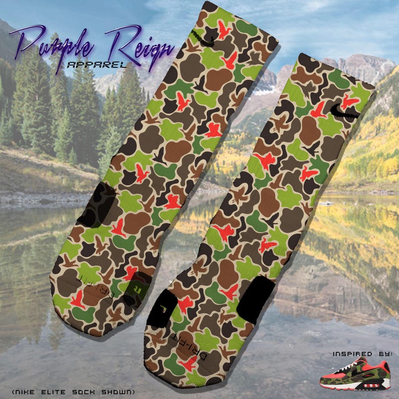 May include: A pair of camouflage patterned socks with orange and green accents. The socks feature a bird design and the text "Dri-Fit" on one sock. The text "Purple Reign Apparel" is visible at the top of the image.