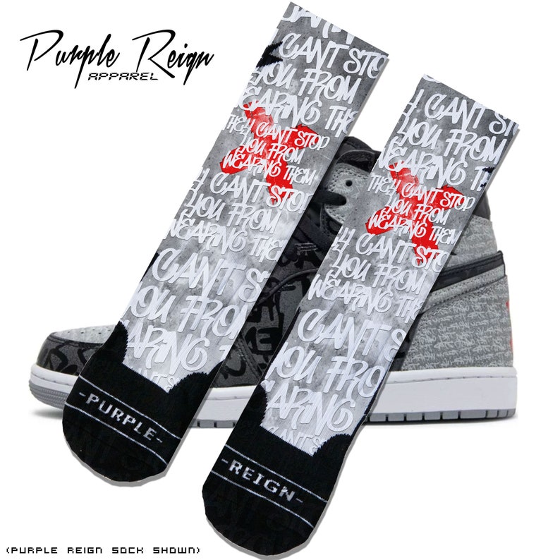 May include: A pair of black and gray socks with the text "Can't Stop You From Wearing Them" printed on them. The socks are shown with a gray and black sneaker.