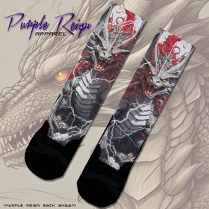 Könnte beinhalten: Ein Paar schwarze Socken mit einem weißen Drachen-Design. Der Drache ist von Blitzen umgeben und hat rote Akzente. Die Socken werden von Purple Reign Apparel hergestellt.