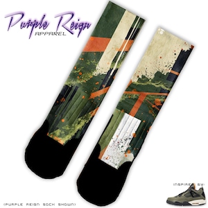 Op de afbeelding: Twee sokken met zwarte tenen en hielen, met een abstract groen, oranje en wit ontwerp. De sokken hebben de tekst "Purple Reign Apparel" in paarse letters. Het ontwerp is geïnspireerd op een groene en zwarte sneaker.