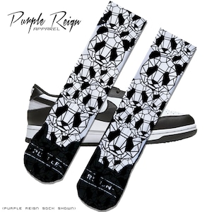 May include: A pair of white socks with a black geometric panda pattern. The socks are shown with a black and white sneaker. The text "Purple Reign Apparel" is visible in the image.