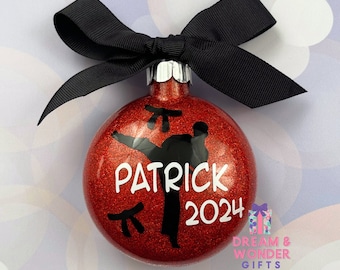 May include: Red glitter Christmas ornament with a black silhouette of a person doing a karate kick. The ornament is personalized with the name "Patrick" and the year "2024".