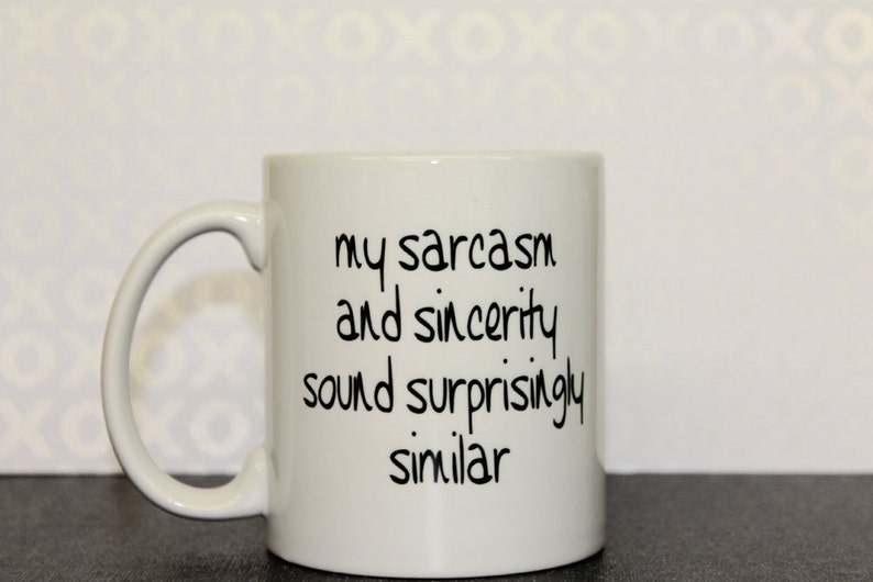 Puede incluir: Taza de caf&eacute; de cer&aacute;mica blanca con texto negro que dice "mi sarcasmo y sinceridad suenan sorprendentemente similares".
