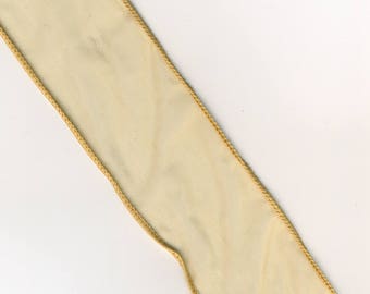 Puede incluir: Una cinta de color amarillo pálido con un borde dorado.