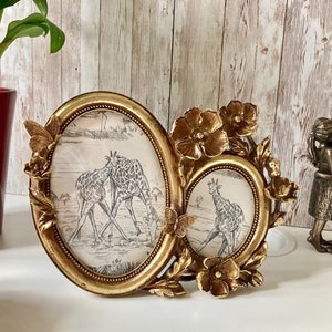 Peut inclure: Un cadre photo double en or avec des accents floraux ornés. Le cadre présente deux ouvertures ovales, chacune avec une impression en noir et blanc de girafes.