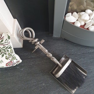Peut inclure: Un ensemble de cheminée en métal argenté avec une poignée torsadée et une brosse fixée à un petit balai.