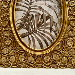 Peut inclure: Cadre photo ovale dor&eacute; avec un motif floral orn&eacute;. Le cadre a un bord sur&eacute;lev&eacute; et une finition lisse.