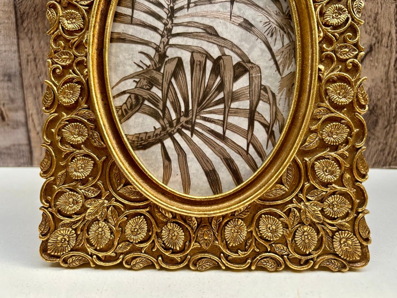 Peut inclure: Cadre photo ovale dor&eacute; avec un motif floral orn&eacute;. Le cadre a un bord sur&eacute;lev&eacute; et une finition lisse.