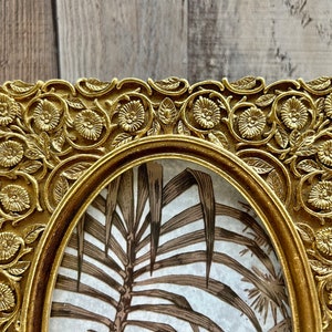 Peut inclure: Un cadre photo orn&eacute; de couleur or avec un motif floral d&eacute;taill&eacute;. Le cadre est de forme ovale et a un bord sur&eacute;lev&eacute;. Le cadre est vide et pr&ecirc;t &agrave; accueillir une photo.