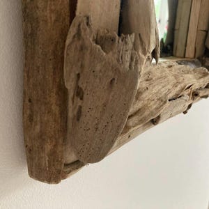 May include: Close-up of a rustic wooden mirror frame made from driftwood. The frame is natural brown with a rough, textured surface.