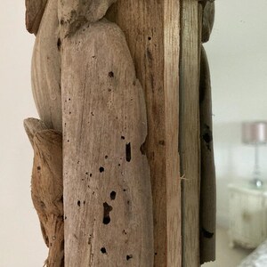 May include: Close-up of a wooden frame with a natural wood finish. The frame is made of multiple pieces of wood that have been joined together. The wood has a rustic look with knots and grain patterns. The frame is perfect for a mirror or a picture.