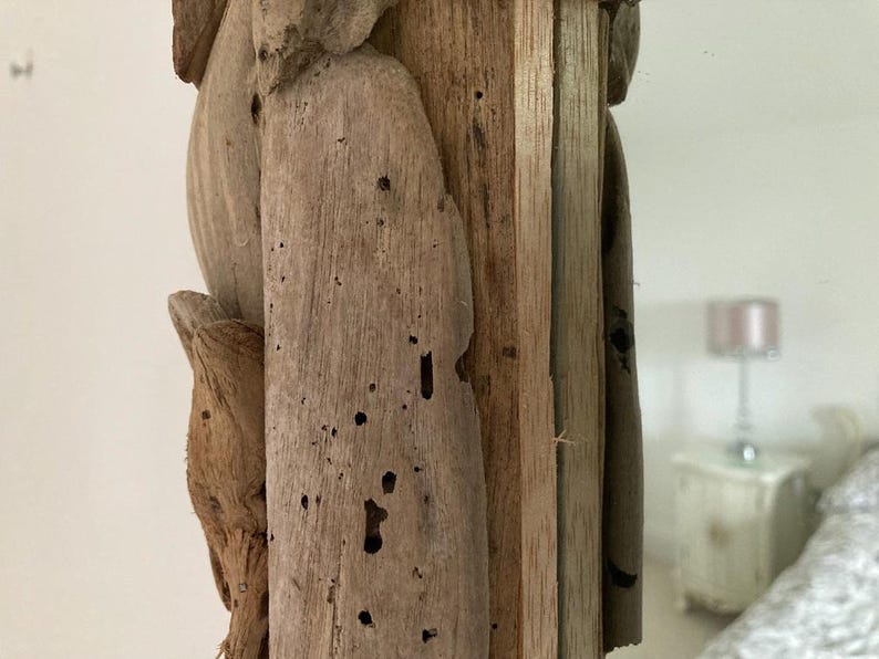 May include: Close-up of a wooden frame with a natural wood finish. The frame is made of multiple pieces of wood that have been joined together. The wood has a rustic look with knots and grain patterns. The frame is perfect for a mirror or a picture.