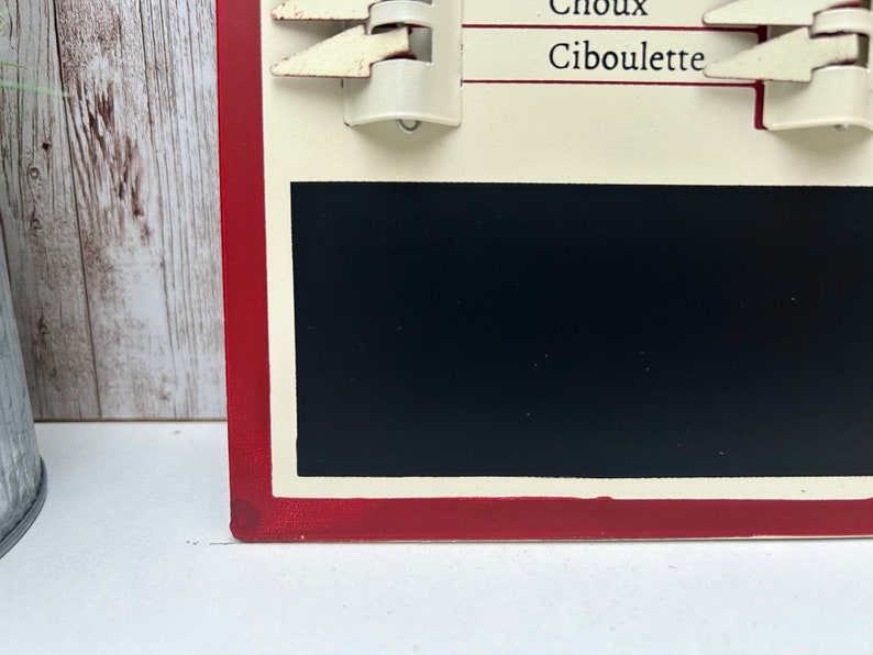 Op de afbeelding: Een rood en wit krijtbord met een zwart krijtbord inzetstuk. Het bord heeft een witte rand en de woorden "Choux Cibulette" in zwart.