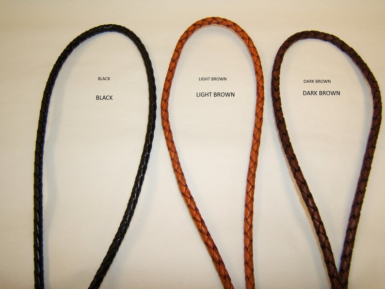 May include: Three braided leather cords in black, light brown, and dark brown. The text "BLACK", "LIGHT BROWN", and "DARK BROWN" are above each cord. The cords are likely for jewelry or crafting.