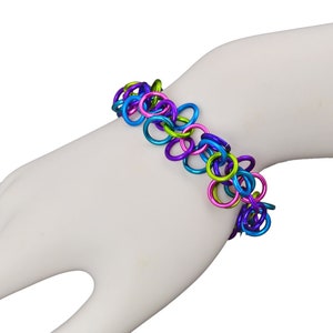 May include: A colorful bracelet made of linked metal rings in shades of blue, green, and pink.