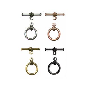 May include: Four sets of silver, copper, gold, and black toggle clasps. Each clasp has a bar with a decorative end and a ring with a decorative edge.