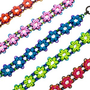 May include: Five colourful bracelets made of linked metal rings in the shape of flowers. The bracelets are in shades of orange, pink, teal, green, and magenta.