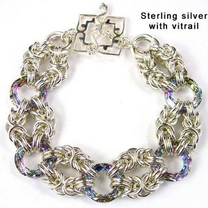 May include: A silver bracelet with a chainmail design and iridescent accents. The bracelet has a clasp with a decorative design. Sterling silver with vitrail.