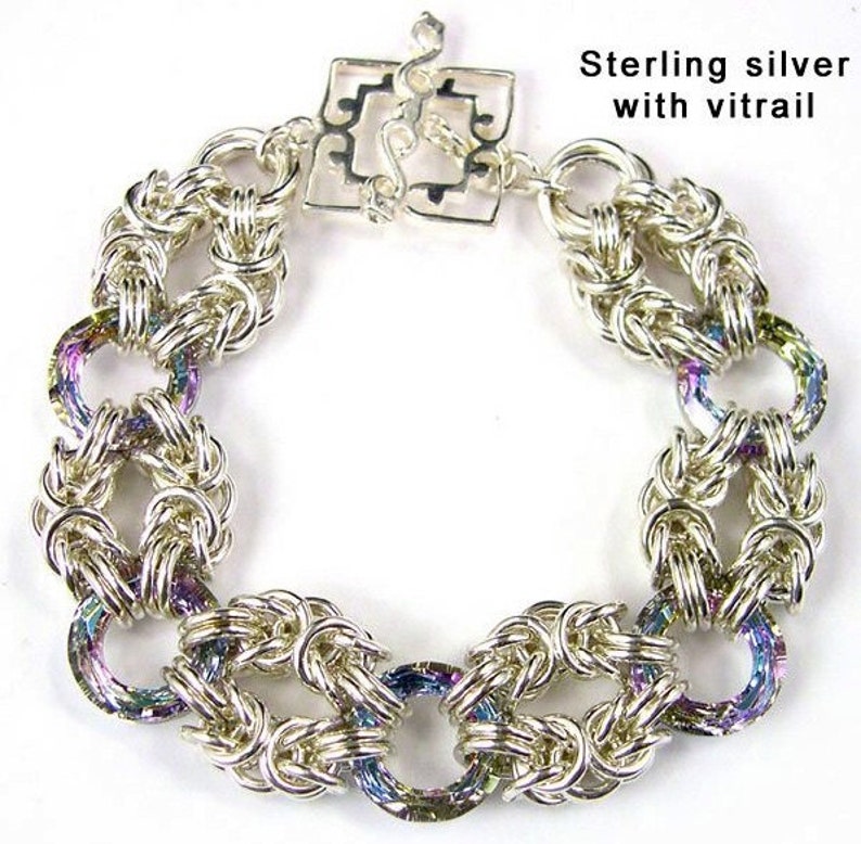 May include: A silver bracelet with a chainmail design and iridescent accents. The bracelet has a clasp with a decorative design. Sterling silver with vitrail.