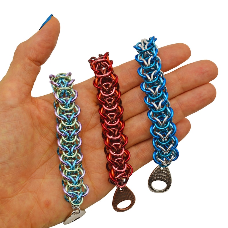 Puede incluir: Tres pulseras de malla de cadena en diferentes colores. Las pulseras est&aacute;n hechas de anillos de metal y tienen un cierre de metal martillado. Las pulseras son azules, rojas y verdes.