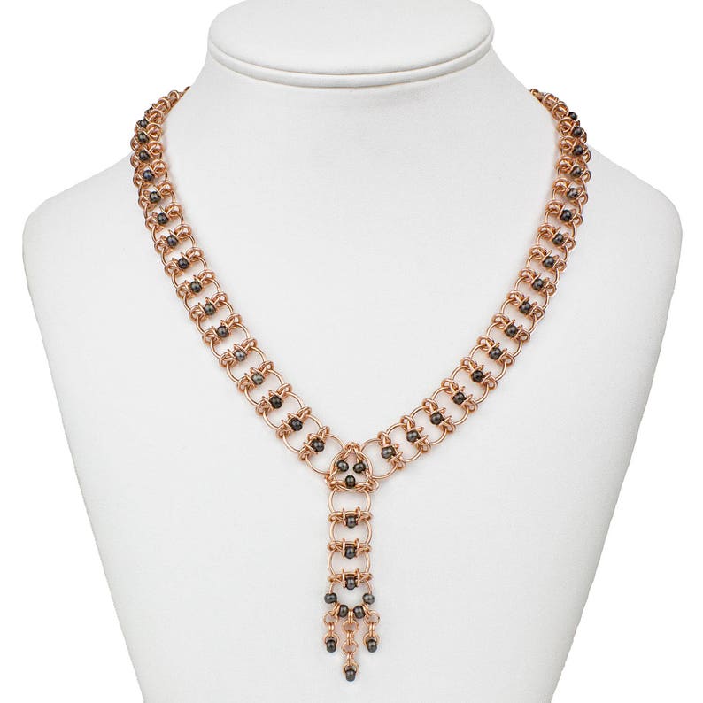 Op de afbeelding: Een ros&eacute;gouden ketting met een zwarte kralenketting en een hangende hanger. De hanger is gemaakt van meerdere zwarte kralen en ros&eacute;gouden schakels.