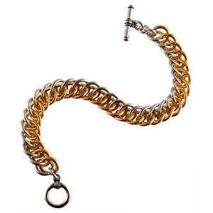 May include: A gold and silver chain bracelet with a toggle clasp. The bracelet is made of two different metals, with the gold portion on the bottom and the silver portion on the top.