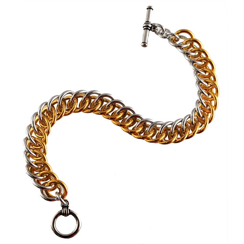 May include: A gold and silver chain bracelet with a toggle clasp. The bracelet is made of two different metals, with the gold portion on the bottom and the silver portion on the top.