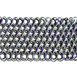 May include: Close-up of a section of chainmail. The chainmail is made of interlocking silver-colored rings, with some rings featuring a purple hue. The pattern is dense and creates a textured surface, suitable for jewelry or costume design.