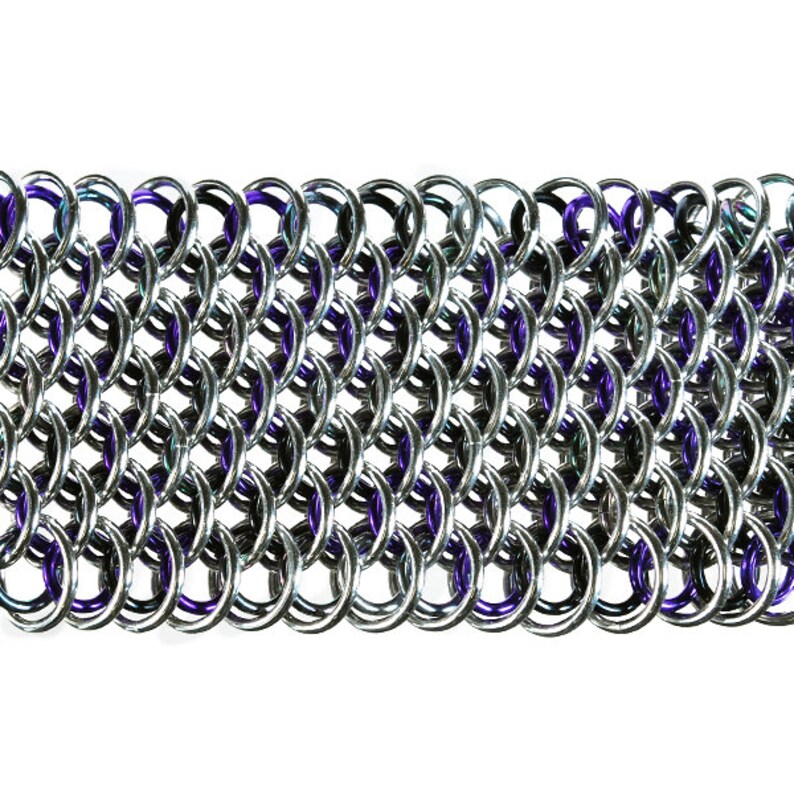 May include: Close-up of a section of chainmail. The chainmail is made of interlocking silver-colored rings, with some rings featuring a purple hue. The pattern is dense and creates a textured surface, suitable for jewelry or costume design.