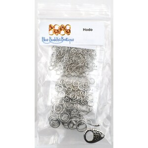 May include: A clear plastic bag containing a large quantity of silver jump rings, a silver lobster clasp, and a small white label with the text "Hodo" and "Blue Buddha Boutique".